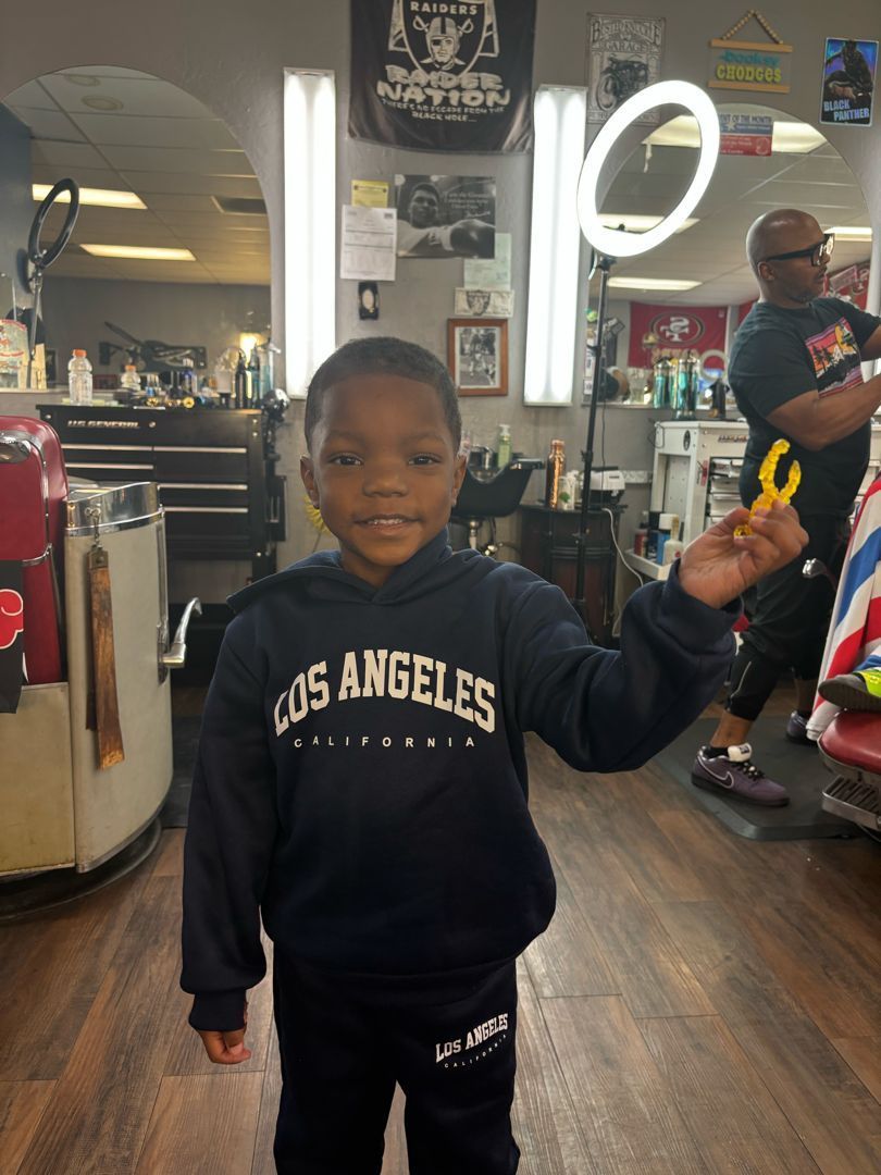 A young client smiling after his cut, barber in the background